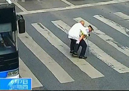 شرطي يحمل مسناً على ظهره ليعبر الطريق (فيديو)