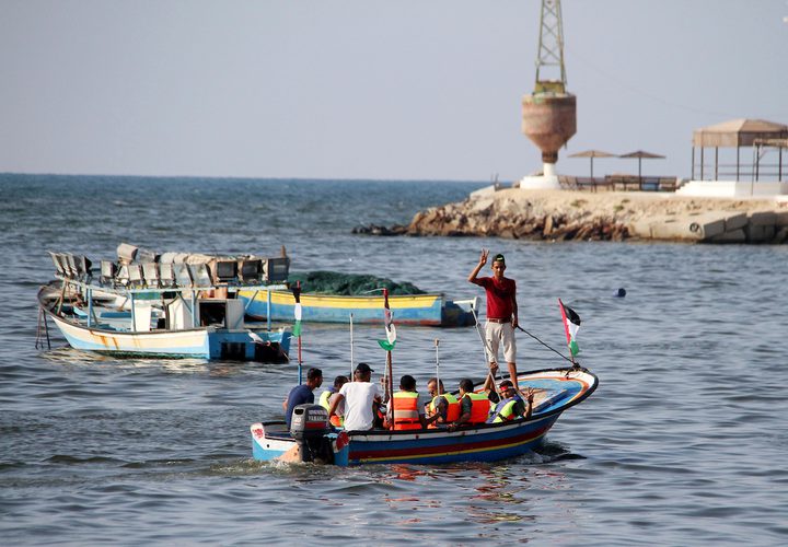 فلسطينيون يركبون قوارب صيد خلال مسيرة لكسر الحصار الإسرائيلي على قطاع غزة ، في البحر في مدينة غزة .