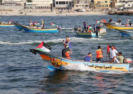 فلسطينيون يركبون قوارب صيد خلال مسيرة لكسر الحصار الإسرائيلي على قطاع غزة ، في البحر في مدينة غزة .