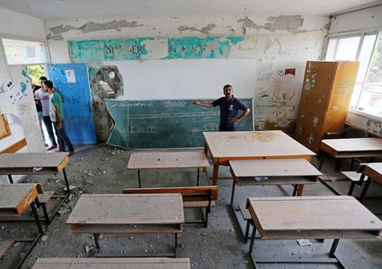 فلسطينيون يتفقدون فصلاً من مدرسة تديرها الأمم المتحدة تضررت جراء القصف الإسرائيلي في اليوم السابق ، في خان يونس في جنوب قطاع غزة في 15 سبتمبر 2018.