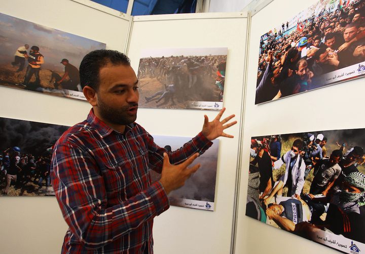 مواطنون يحضرون معرض صور بعنوان "صحفيون على خط النار"، في مدينة غزة.