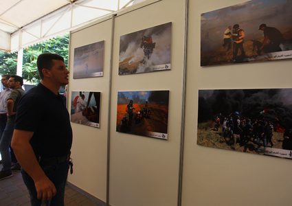 مواطنون يحضرون معرض صور بعنوان "صحفيون على خط النار"، في مدينة غزة.