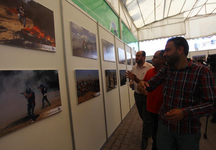 مواطنون يحضرون معرض صور بعنوان "صحفيون على خط النار"، في مدينة غزة.