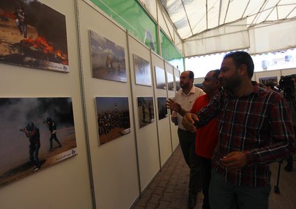 مواطنون يحضرون معرض صور بعنوان "صحفيون على خط النار"، في مدينة غزة.