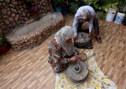 سيدة فلسطينية تطحن القمح بواسطة مطحنة حجرية داخل منزلها، في قرية جلبون بالقرب من مدينة جنين في الضفة الغربية.