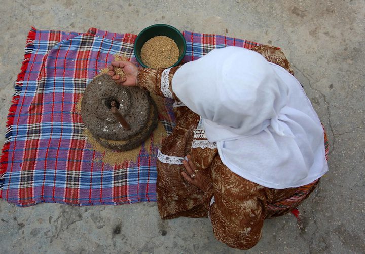 سيدة فلسطينية تطحن القمح بواسطة مطحنة حجرية داخل منزلها، في قرية جلبون بالقرب من مدينة جنين في الضفة الغربية.
