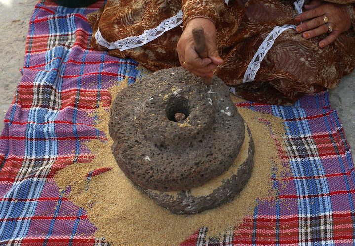 سيدة فلسطينية تطحن القمح بواسطة مطحنة حجرية داخل منزلها، في قرية جلبون بالقرب من مدينة جنين في الضفة الغربية.