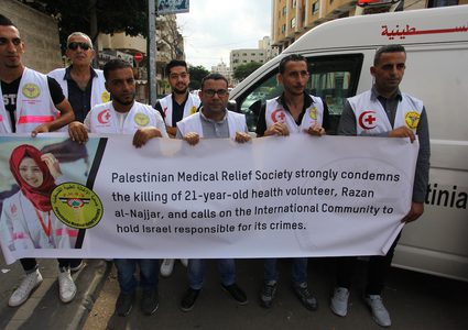 مسعفون فلسطينيون يحملون لافتات أثناء الاحتجاج للمطالبة بحمايتهم أمام مكتب الصليب الأحمر في غزة.