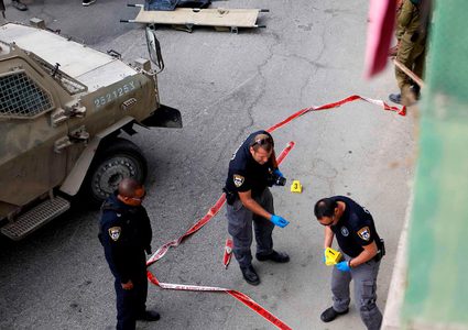 قوات الأمن الإسرائيلية تقف حول جثة فلسطيني في مسرح عملية طعن في مدينة الخليل بالضفة الغربية.