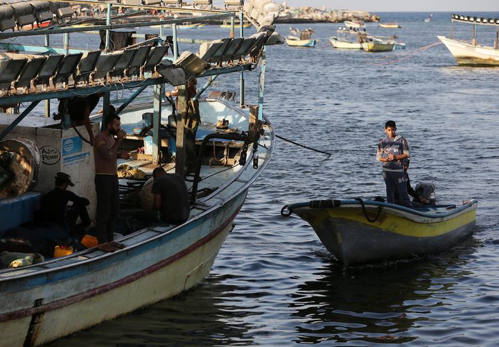 صيادون فلسطينيون يعملون على قوارب الصيد الخاصة بهم في البحر في الميناء البحري في مدينة غزة.