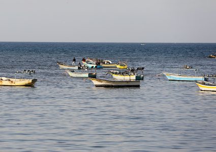 صيادون فلسطينيون يعملون على قوارب الصيد الخاصة بهم في البحر في الميناء البحري في مدينة غزة.