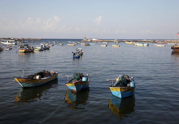 صيادون فلسطينيون يعملون على قوارب الصيد الخاصة بهم في البحر في الميناء البحري في مدينة غزة.