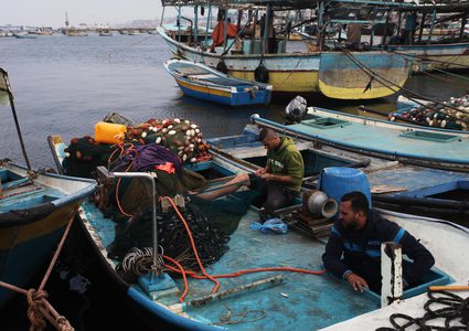 صيادون فلسطينيون يعملون على قوارب الصيد الخاصة بهم في البحر في الميناء البحري في مدينة غزة في15 نوفمبر 2018.