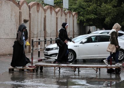 فلسطينيون يسيرون في شارع غمرته المياه في يوم ممطر في مدينة غزة في 20 ديسمبر عام 2018.