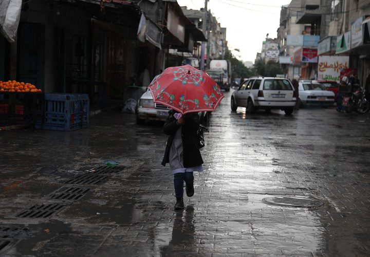 فلسطينيون يسيرون في شارع غمرته المياه في يوم ممطر في بيت لاهيا شمال قطاع غزة في 27 ديسمبر 2018.