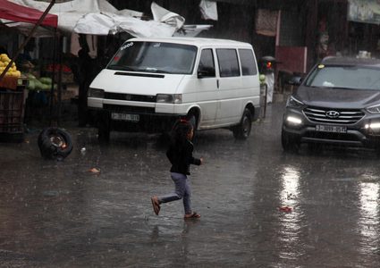 فلسطينيون يسيرون في شارع غمرته المياه في يوم ممطر في بيت لاهيا شمال قطاع غزة في 27 ديسمبر 2018.