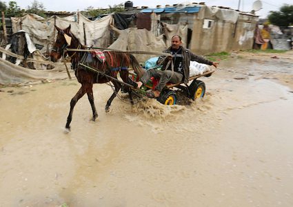 رجل فلسطيني يركب عربة خيل في يوم ممطر في مخيم نهر البارد للاجئين في خان يونس جنوب قطاع غزة في 30 كانون الأول / ديسمبر ، 2018.