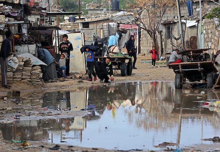 فلسطينيون يقفون في الشارع في يوم ممطر في مخيم نهر البارد للاجئين في خان يونس جنوب قطاع غزة في 30 كانون الأول / ديسمبر ، 2018.