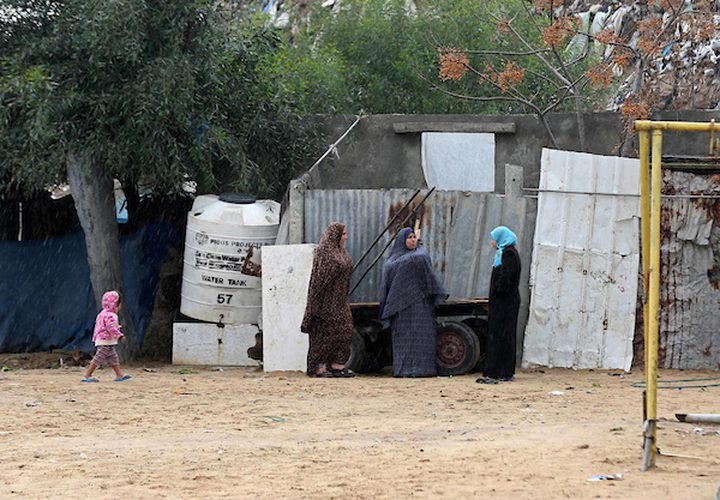 نساء فلسطينيات يقفن في الشارع في يوم ممطر في مخيم نهر البارد للاجئين في خان يونس جنوب قطاع غزة في 30 كانون الأول / ديسمبر 2018.