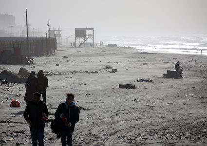 فلسطينيون يسيرون على شاطئ مدينة غزة في يوم عاصف ، في 7 يناير ، 2019.
