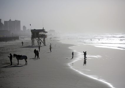 فلسطينيون يسيرون على شاطئ مدينة غزة في يوم عاصف ، في 7 يناير ، 2019.