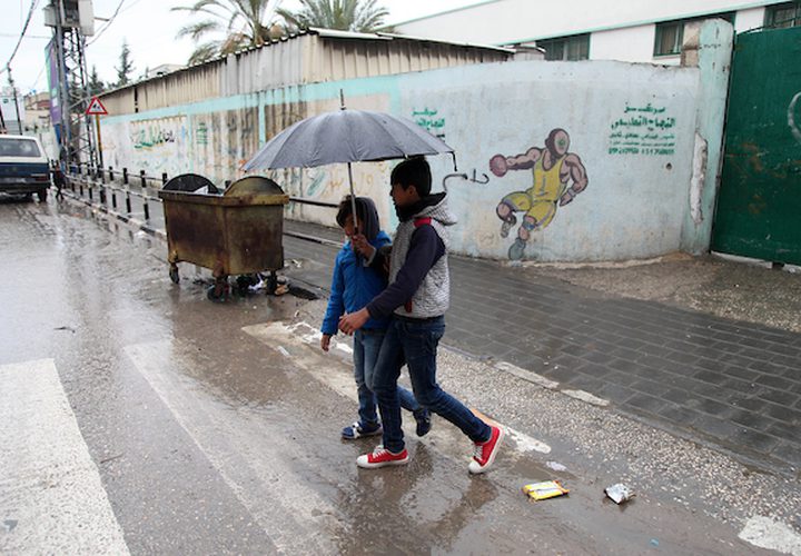 فلسطينيون يسيرون في شارع غمرته المياه في يوم ممطر ، في مدينة غزة ، في 2 مارس ، 2019.