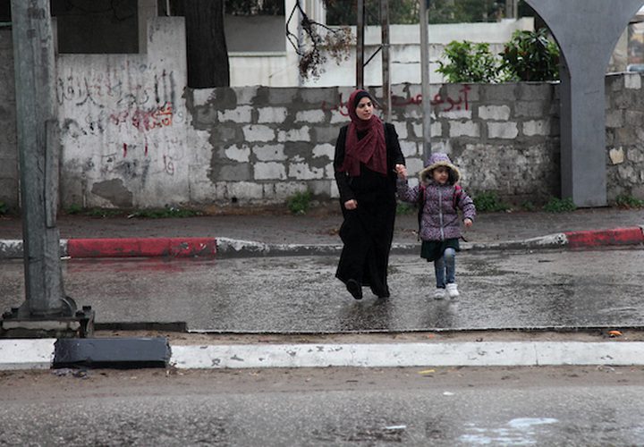 فلسطينيون يسيرون في شارع غمرته المياه في يوم ممطر ، في مدينة غزة ، في 2 مارس ، 2019.