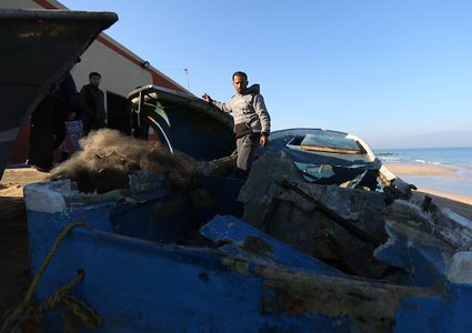 صيادون يتفقدون قاربهم المستهدف بالقصف الإسرائيلي على غزة