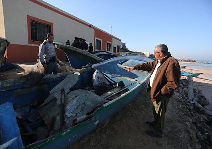 صيادون فلسطينيون يتفقدون قاربهم المستهدف بغارة جوية إسرائيلية على شاطئ دير البلح وسط قطاع غزة في 10 مارس / آذار 2019.