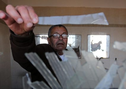 صيادون فلسطينيون يتفقدون قاربهم المستهدف بغارة جوية إسرائيلية على شاطئ دير البلح وسط قطاع غزة في 10 مارس / آذار 2019.