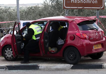 يقف أفراد من قوات الاحتلال الإسرائيلي حراسة بجوار سيارة في موقع الهجوم على مفترق آرييل المؤدي إلى مستوطنة أرييل الإسرائيلية في الضفة الغربية في 17 مارس 2019.