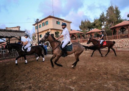 متسابقون فلسطينيون يقفزون مع أحصنتهم خلال مسابقة الفروسية المحلية ، في شمال مدينة غزة .