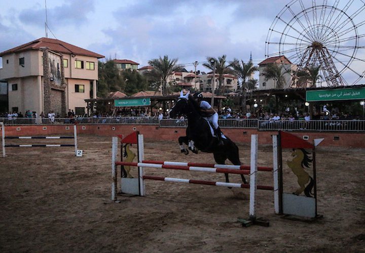 متسابقون فلسطينيون يقفزون مع أحصنتهم خلال مسابقة الفروسية المحلية ، في شمال مدينة غزة .