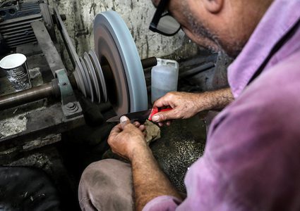 عمال في غزة، يقومون بسن السكاكين، بورشة عمل، قبيل عيد الأضحى، حيث يستخدمونها لذبح الماشية والأغنام في عيد الأضحى.