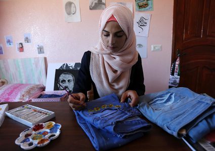 الفنانة الفلسطينية منال الاسطل 20 عاماً، ترسم على الملابس، في منزلها بخانيونس في قطاع غزة.