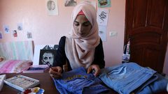 الفنانة الفلسطينية منال الاسطل 20 عاماً، ترسم على الملابس، في منزلها بخانيونس في قطاع غزة.