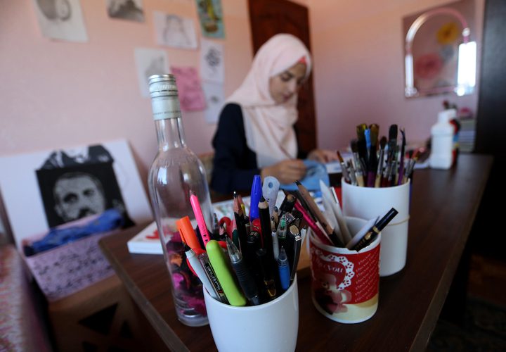 الفنانة الفلسطينية منال الاسطل 20 عاماً، ترسم على الملابس، في منزلها بخانيونس في قطاع غزة.