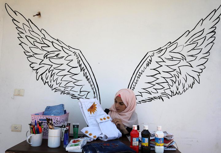 الفنانة الفلسطينية منال الاسطل 20 عاماً، ترسم على الملابس، في منزلها بخانيونس في قطاع غزة.