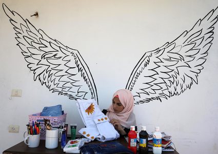 الفنانة الفلسطينية منال الاسطل 20 عاماً، ترسم على الملابس، في منزلها بخانيونس في قطاع غزة.