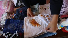 الفنانة الفلسطينية منال الاسطل 20 عاماً، ترسم على الملابس، في منزلها بخانيونس في قطاع غزة.