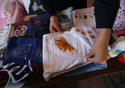 الفنانة الفلسطينية منال الاسطل 20 عاماً، ترسم على الملابس، في منزلها بخانيونس في قطاع غزة.