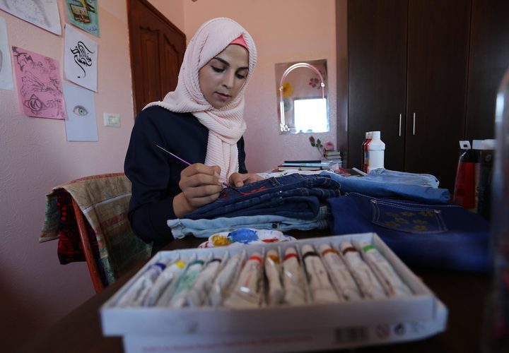 الفنانة الفلسطينية منال الاسطل 20 عاماً، ترسم على الملابس، في منزلها بخانيونس في قطاع غزة.