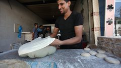 مهارة وإتقان يرقّق بكلتا يديه، قطعة عجين يتلقفها بسرعة بين كفّيه عدة مرات، ويصنع منها رغيف خبز دائري كبير.