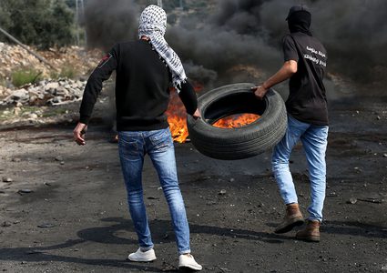 متظاهرون يحرقون الإطارات أثناء المواجهات مع قوات الاحتلال الإسرائيلي خلال مسيرة كفر قدوم السلمية الأسبوعية.