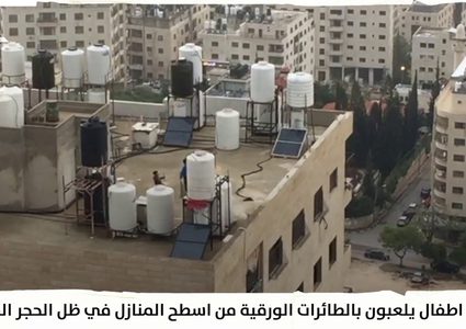 أطفال يلعبون بالطائرات الورقية من أسطح المنازل بظل الحجر المنزلي