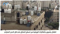 أطفال يلعبون بالطائرات الورقية من أسطح المنازل بظل الحجر المنزلي