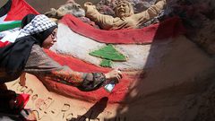 الفنانة الفلسطينية رنا الرملاوي ، 25 سنة ، ترسم علم لبنان على تمثال رملي في منزلها ، تضامناً مع اللبنانيين ، في مدينة غزة.