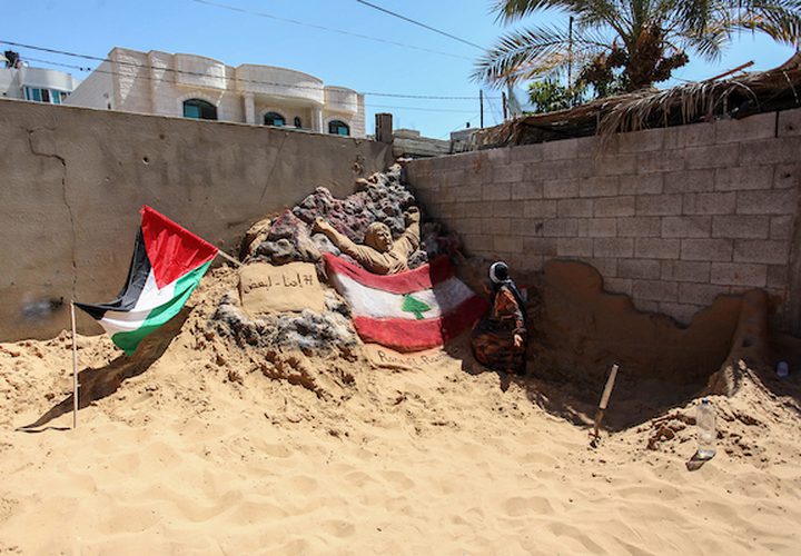 الفنانة الفلسطينية رنا الرملاوي ، 25 سنة ، ترسم علم لبنان على تمثال رملي في منزلها ، تضامناً مع اللبنانيين ، في مدينة غزة.