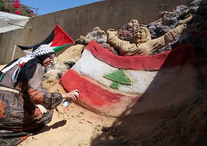 الفنانة الفلسطينية رنا الرملاوي ، 25 سنة ، ترسم علم لبنان على تمثال رملي في منزلها ، تضامناً مع اللبنانيين ، في مدينة غزة.