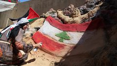 الفنانة الفلسطينية رنا الرملاوي ، 25 سنة ، ترسم علم لبنان على تمثال رملي في منزلها ، تضامناً مع اللبنانيين ، في مدينة غزة.